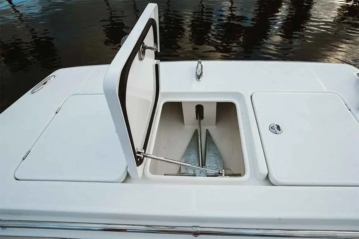 Open boat storage compartment revealing metal anchors inside, with a white deck and reflective water in the background.